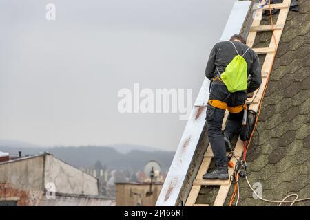 A man works on the roof repair, installs sheet metal on top of the gable wall Stock Photo