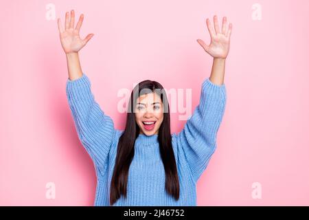 Portrait of attractive cheerful brown-haired girl rising hands up having fun isolated over pink pastel color background Stock Photo