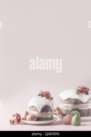 Glazed Easter cakes decorated with dry tea rose flowers on pastel pink background. Easter composition with cakes, roses and chocolate eggs. Easter background with copy space for your design. Stock Photo