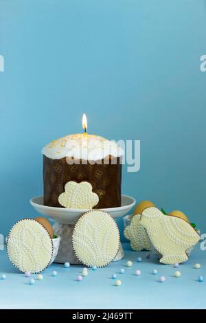 Easter composition, traditional Easter cake, colored eggs and gingerbread on a blue background. Stock Photo