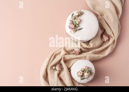 Glazed Easter cakes decorated with dry tea rose flowers on pastel background. Easter composition with cakes, roses and napkin. Easter background with copy space for your design. Stock Photo