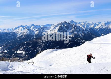 A woman wearing skis and carrying poles climbs up close to the summit of Patscherkofel mountain in the Austrian Alps. Stock Photo