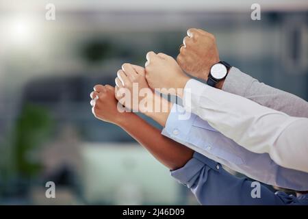 We always stand together. Shot of a group of unrecognizable businesspeople holding up their fists at work. Stock Photo