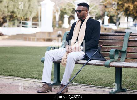 Insanity and genius is measured only by success. Shot of a young man sitting on a bench in a park. Stock Photo