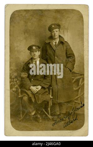Original WW1 era postcard  of a pair of Royal Engineers, pals, their cap badges denote that they are both Royal engineers. They both wear greatcoats, one has visible arm band, denoting he has be wounded. They look happy enough to be invalided out of the war even temporarily. From the studio of Albert England, 60 High St. Barnet, London, England, U.K. 1914-1918 Stock Photo