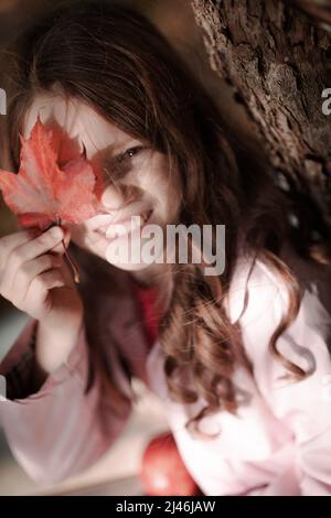 Portrait of a smiling girl in the park with autumn leaves. Stock Photo