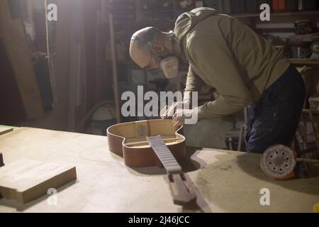 Carpenter repairs guitar. Acoustic guitar without body cover. Stock Photo