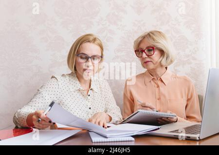 Mature business women discuss documents in the home office. Stock Photo