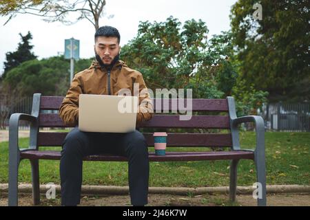 young asian man working with computer in the park Stock Photo
