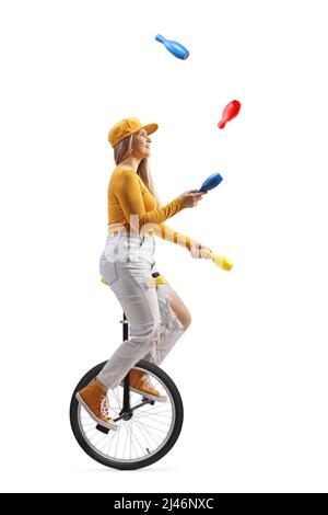Young female riding a unicycle and juggling isolated on white background Stock Photo