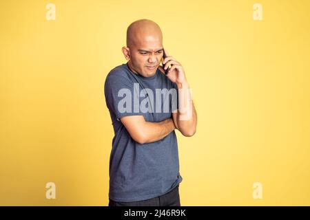 Serious asian bald man listening while calling Stock Photo