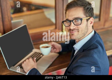 Ive got a lot done today. Portrait of a young businessman using his laptop while sitting in a coffee shop. Stock Photo