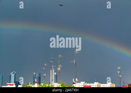 Rainbow over the sky of Madrid next to the skyscrapers on a stormy day with rain and lightning, in Spain. Photography. Stock Photo