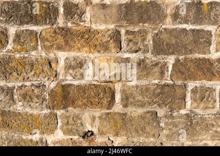 Stone block wall background. Weathered building exterior surface as an abstract texture. Natural dirty facade backdrop. Stock Photo