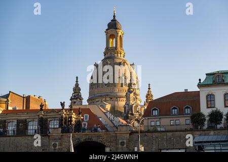 Famous building exterior of the Frauenkirche in the city skyline. Huge church in the evening sunlight. Tourists standing on the Brühl's Terrace. Stock Photo