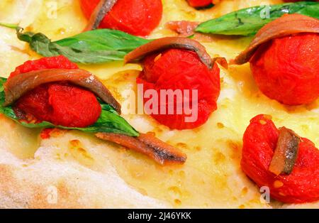 Italian pizza with red tomatoes salted anchovies and basil leaves with fresh mozzarella Stock Photo
