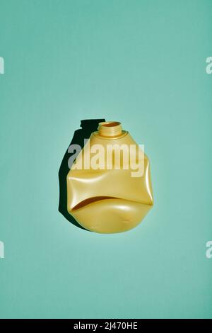 Vertical top-down shot of crumpled yellow plastic bottle on light blue background, conscious consumption and recycling concept Stock Photo