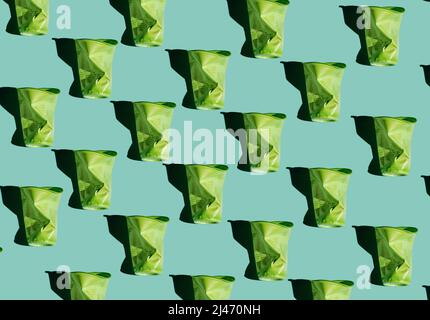 Contemporary seamless pattern flat lay shot of crumpled plastic cups on bluish green background, conscious consumption and plastic waste concept Stock Photo