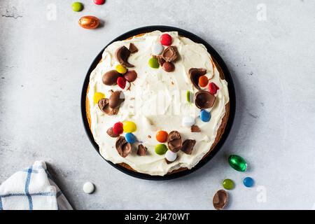 Easter carrot cake with cream cheese, sweet candies and chocolate. Top view. Homemade festive baking. Stock Photo