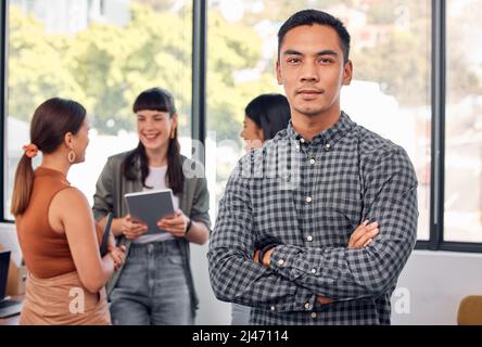 What you see, I stood out till they noticed me. Portrait of a young businessman at the office standing in front of his colleagues having a meeting in Stock Photo