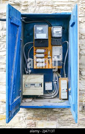 open outdoor vintage blue wooden electrical control cabinet with electricity meters and fuses Stock Photo