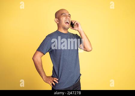 bald young man laughing while making phone call Stock Photo