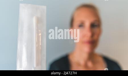 woman holds unopened PCR sars covid 19 nasal test swab to camera Stock Photo