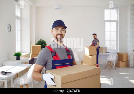 Portrait of happy truck delivery service worker holding cardboard box and smiling Stock Photo