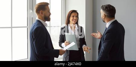 Team of happy, smiling friends and colleagues standing in the office and talking Stock Photo