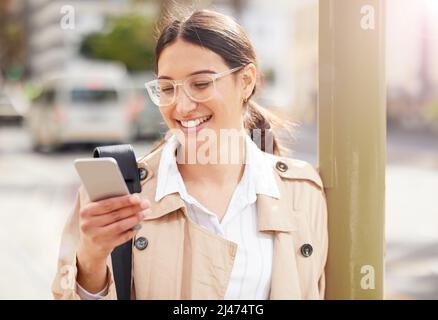 Checking the local hotspots. Shot of a young woman using a smartphone while out in the city. Stock Photo