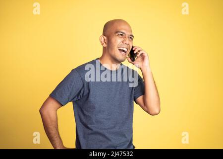 bald man laughing while making phone call Stock Photo