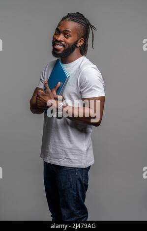 Joyful student holding a pair of spiral notebooks to his chest Stock Photo