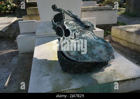 view of  an unusual tombstone with a guitar case sculpture in Père Lachaise cemetery in downtown Paris, France Stock Photo