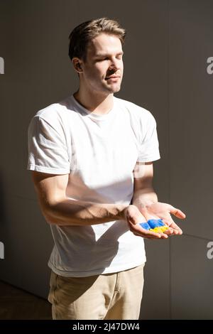 man with closed eyes showing open palms with painted ukrainian flag Stock Photo
