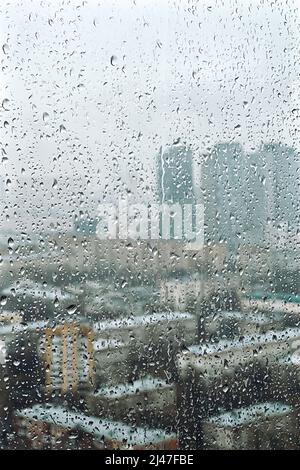 Drops on glass on rainy cloudy day evoke melancholy and sadness. View of city from the window. Selective focus Stock Photo