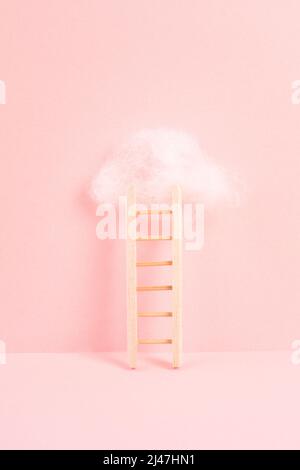 Ladder with a cloud on top, pink rose colored background, copy space, dreaming of success, creative and business concept, achieving new goals Stock Photo