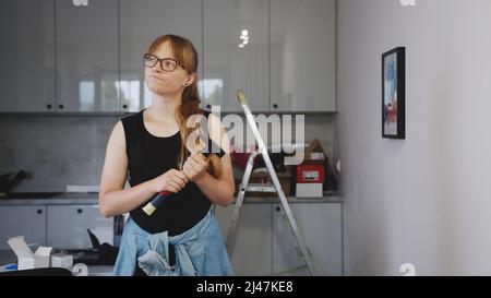 Middle-aged European red-haired woman holding a hammer and thinking about her next renovation project. High quality photo Stock Photo