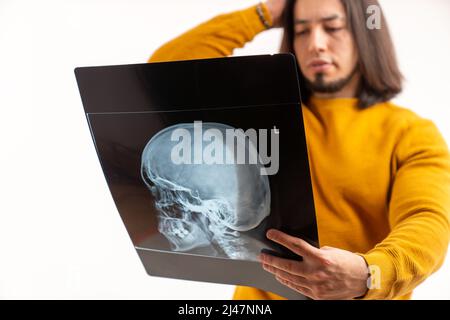 Caucasian bearded man holding his skull x-ray while wearing yellow sweatshirt. Isolated over white background. High quality photo Stock Photo