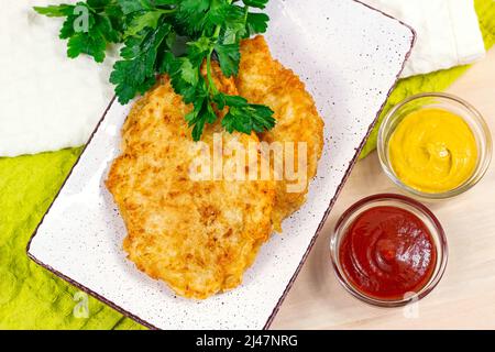 Top view of roasted meat in breading with cheese  and different sauces for dinner. Stock Photo