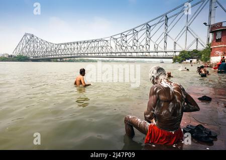 People take a bath in Hooghly River (mouth of the Ganges river) near Howrah Bridge (Rabindra Setu) in Kolkata, India. Stock Photo