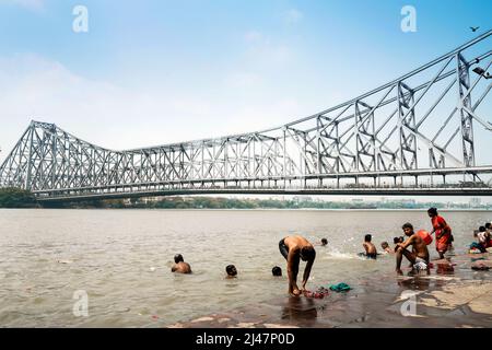 People take a bath in Hooghly River (mouth of the Ganges river) near Howrah Bridge (Rabindra Setu) in Kolkata, India. Stock Photo