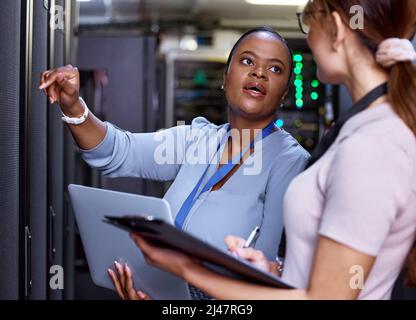 We need these servers running at optimum efficiency. Cropped shot of two attractive young female computer programmers working together in a server Stock Photo