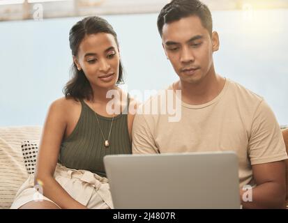Same with moving to a new house. It keeps the balance. Shot of a couple using a laptop at home. Stock Photo