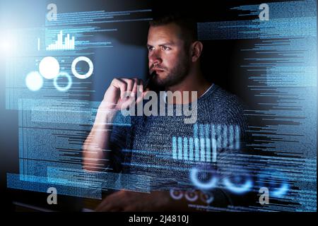 Its the perfect job for a night owl. Shot of a focussed computer programmer working at his computer late at night. Stock Photo