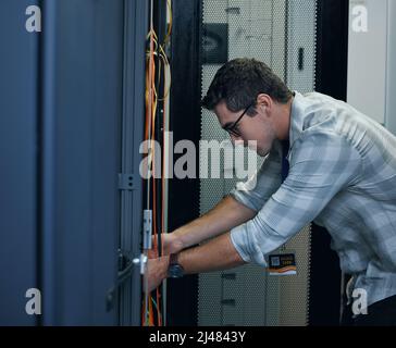 Hes the technician you need. Cropped shot of a handsome young male programmer working in a server room. Stock Photo