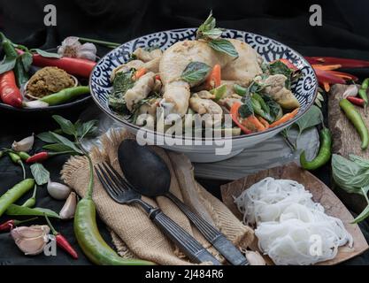 Green curry with Chicken and Green-white varieties of Thai eggplants (Kaeng khiao wan) in Ceramic bowl served with Thai rice noodles (Fermented rice f Stock Photo