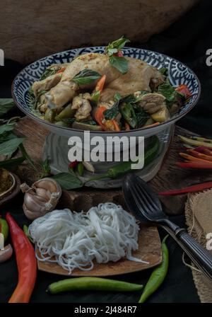 Green curry with Chicken and Green-white varieties of Thai eggplants (Kaeng khiao wan) in Ceramic bowl served with Thai rice noodles (Fermented rice f Stock Photo