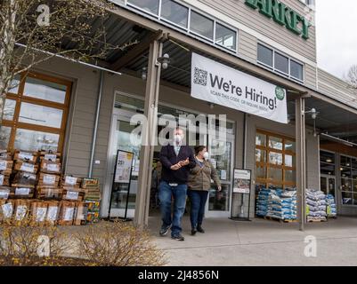 Lynnwood, WA USA - circa April 2022: View of a We Are Hiring sign at the entrance of a Whole Foods Market, above people entering and exiting the store Stock Photo