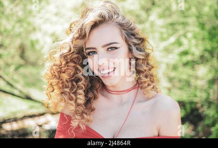 Perfect curly hair. Blonde curly long hair. Perfect woman smiling on spring sunny background. Beauty and perfect health hair. Beauty model with Stock Photo