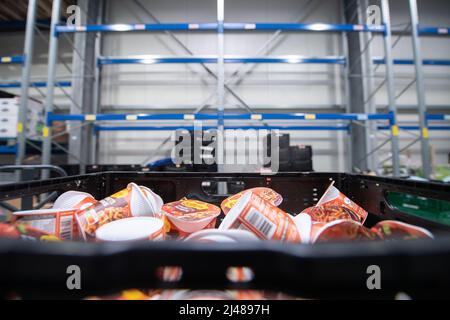 12 April 2022, Hessen, Frankfurt/Main: A box of cups of instant soup stands in front of an empty high rack in the Tafel Frankfurt warehouse. The Tafel in Frankfurt is currently struggling with the fact that it is receiving fewer donations in the face of higher demand. Photo: Sebastian Gollnow/dpa Stock Photo